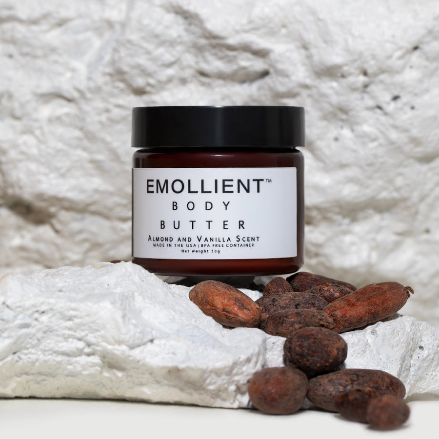Amber jar of almond and vanilla body butter resting on mango butter with roasted almonds.